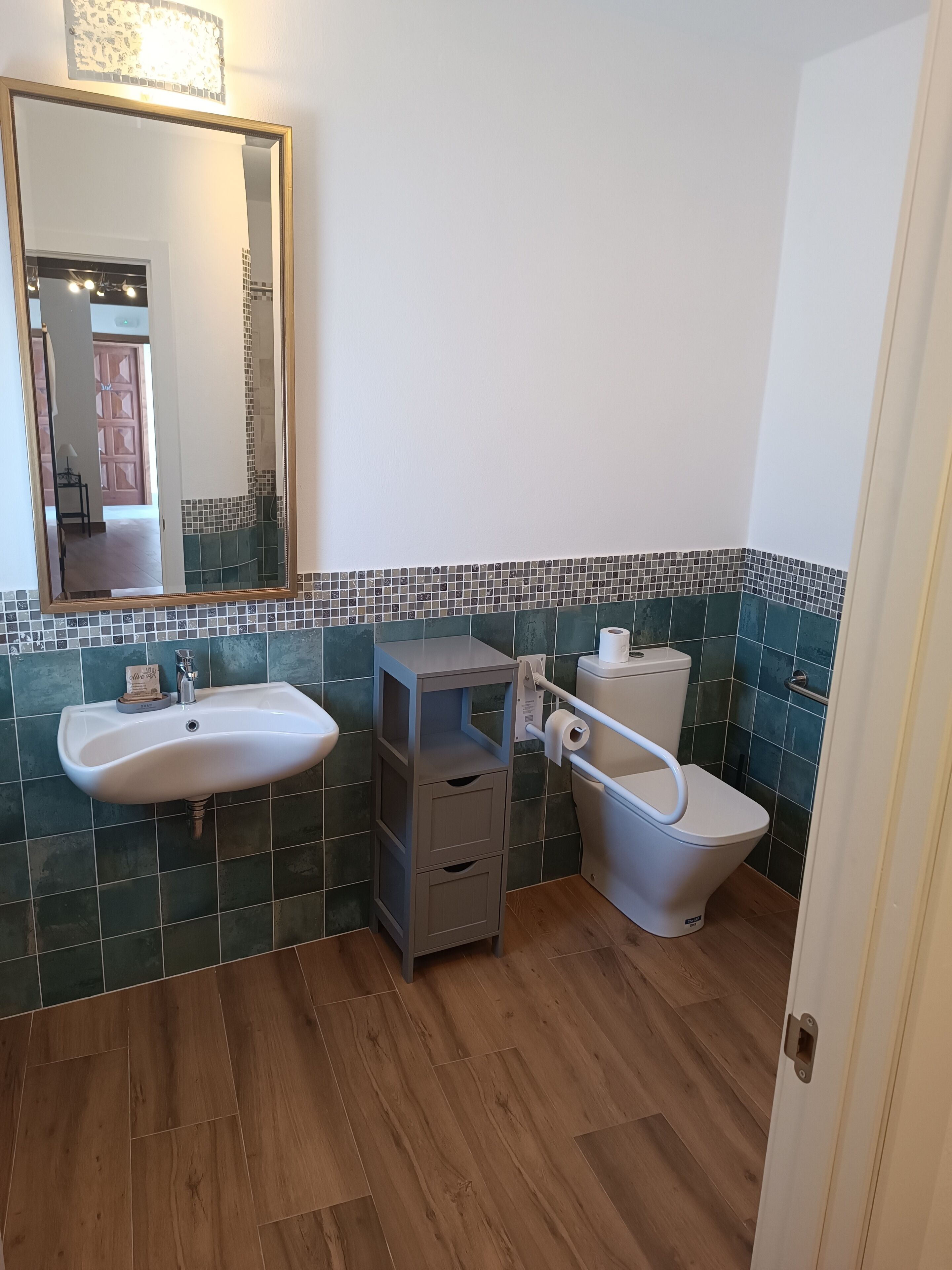 A bathroom with a white sink, a toilet, and a mirror.
