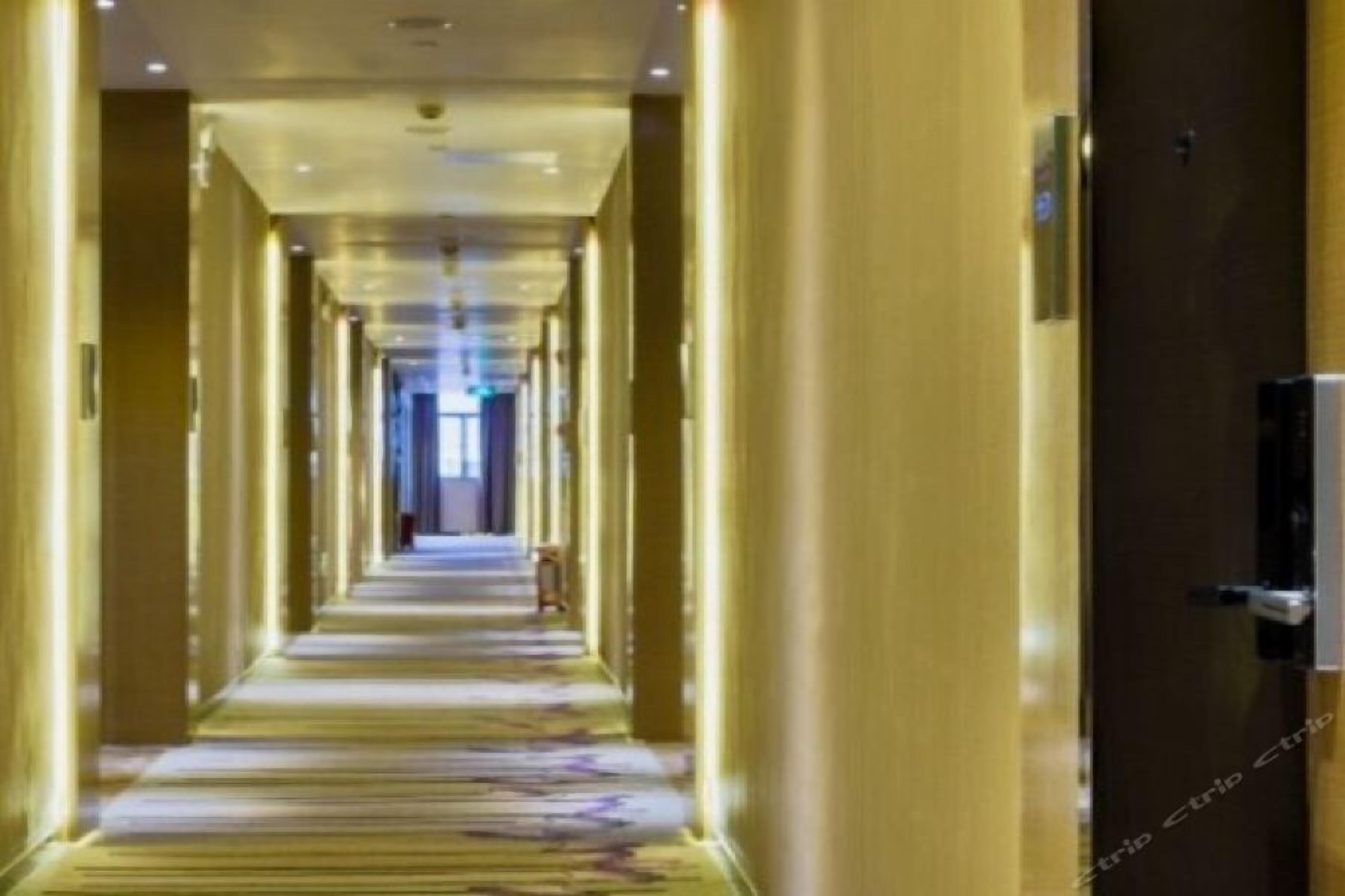 Ein langer, schmaler Hotelgang mit Teppichboden und Holzwänden.