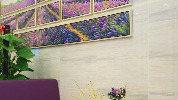 Una hall con un divano viola, un tavolino da caffè in vetro e un composizione floreale.