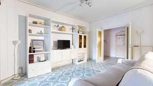 Un salon avec un canapé, un téléviseur et des étagères ornées d’objets décoratifs.