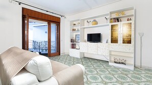 Un salon avec un canapé, un téléviseur et des étagères décoratives.