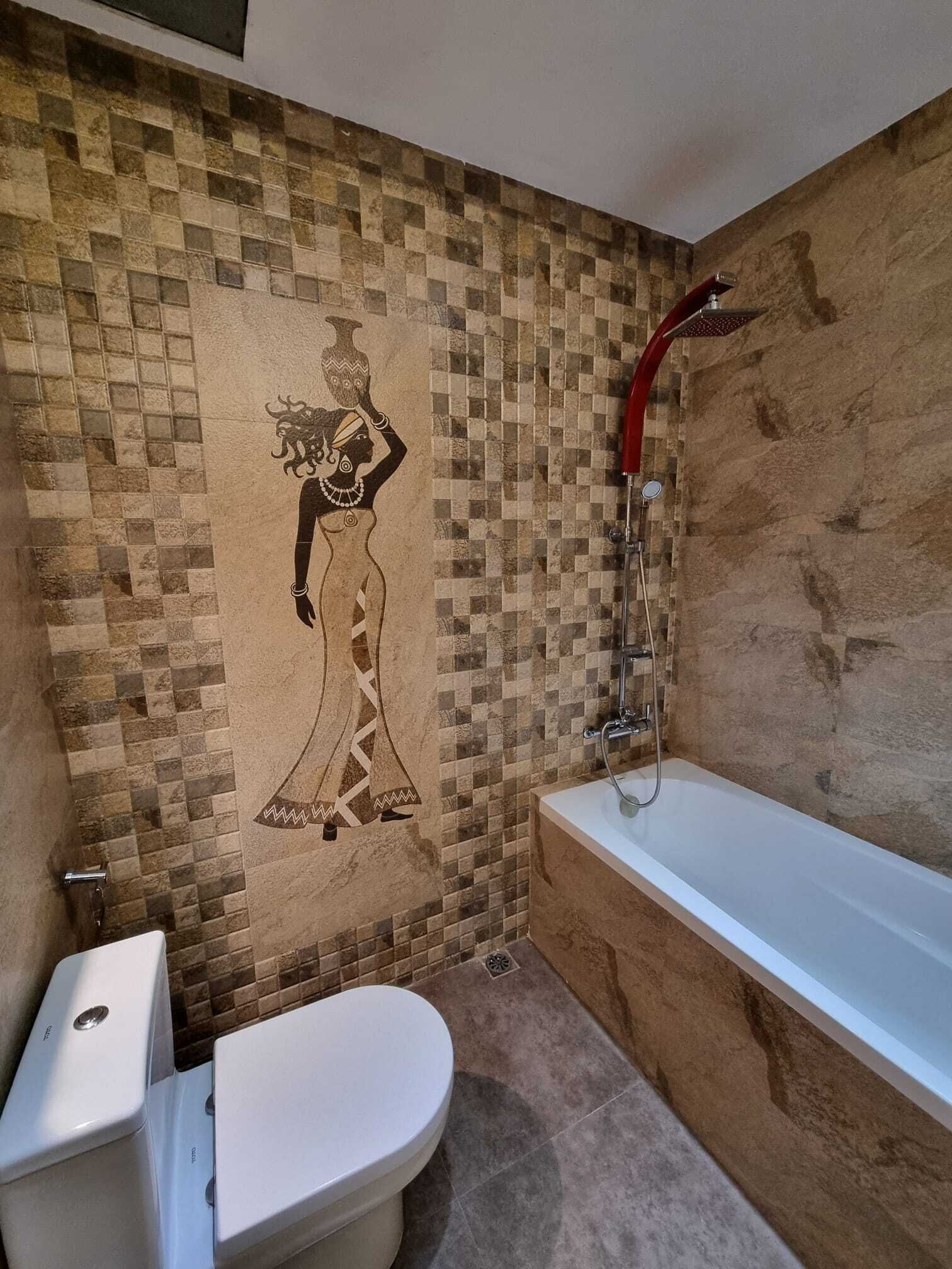 A bathroom with a mosaic wall, a bathtub, and a toilet.