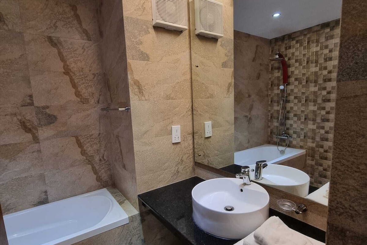 Un baño moderno con bañera, dos lavamanos y un espejo grande.