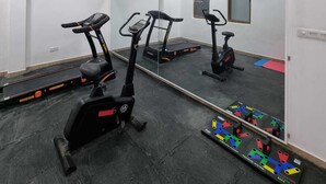 A gym with three stationary bikes, a treadmill, and a mirror reflecting the room. - Utopia Polhena Hotel (Matara)