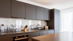 Eine moderne Küche mit dunklen Schränken, einer Edelstahl-Dunstabzugshaube und einer Arbeitsplatte aus Granit.