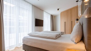 Ein modernes Schlafzimmer mit einem großen Bett, einem flachbildfernseher an der Wand und einem Holzschrank.