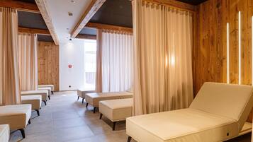 A room with a long row of beige sofas and a single sofa with a wooden headboard.