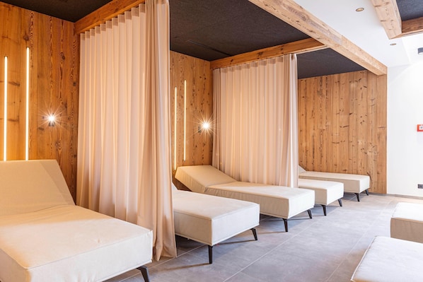 A spa room with four massage beds, wooden walls, and a ceiling with exposed beams.