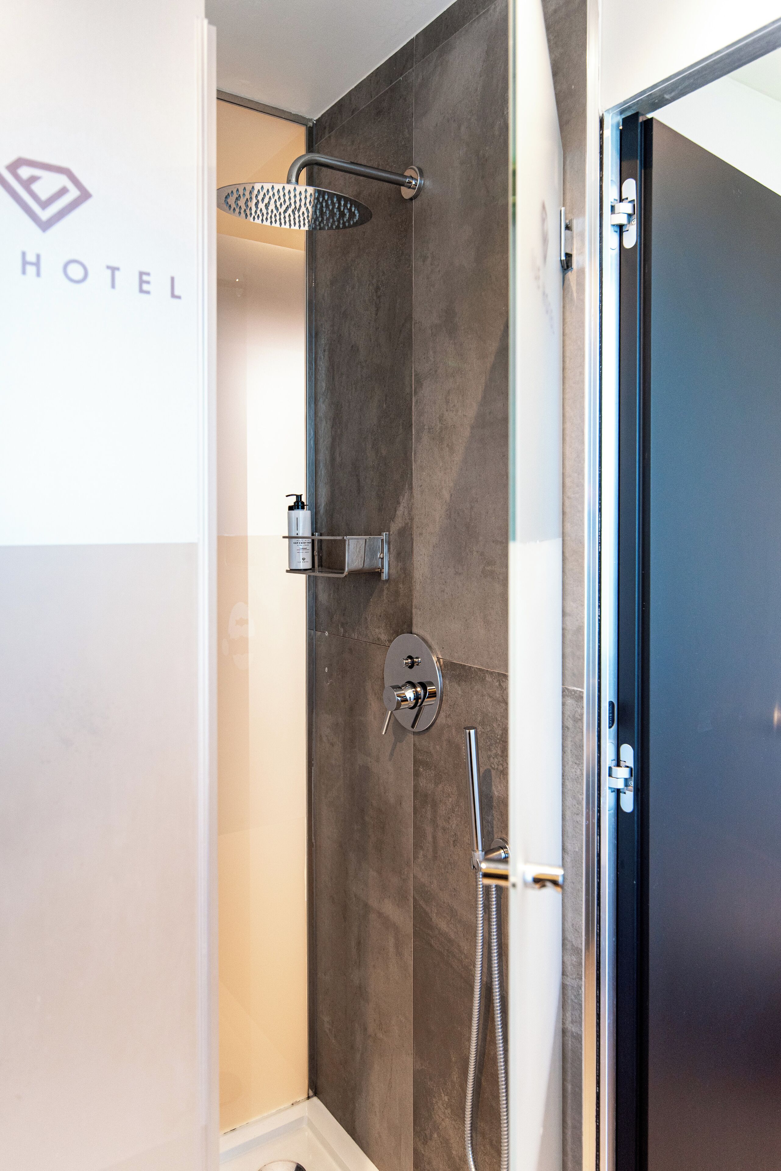 Un baño de hotel moderno con ducha, toallero y retrete.