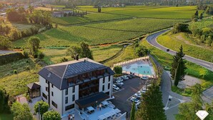 A hotel with a rooftop pool, surrounded by vineyards and a road.