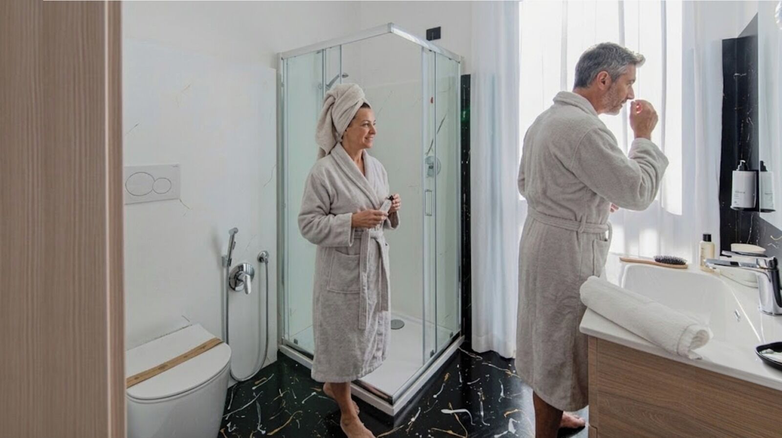 A modern bathroom with a glass shower enclosure, a toilet, and a vanity with a mirror and sink.