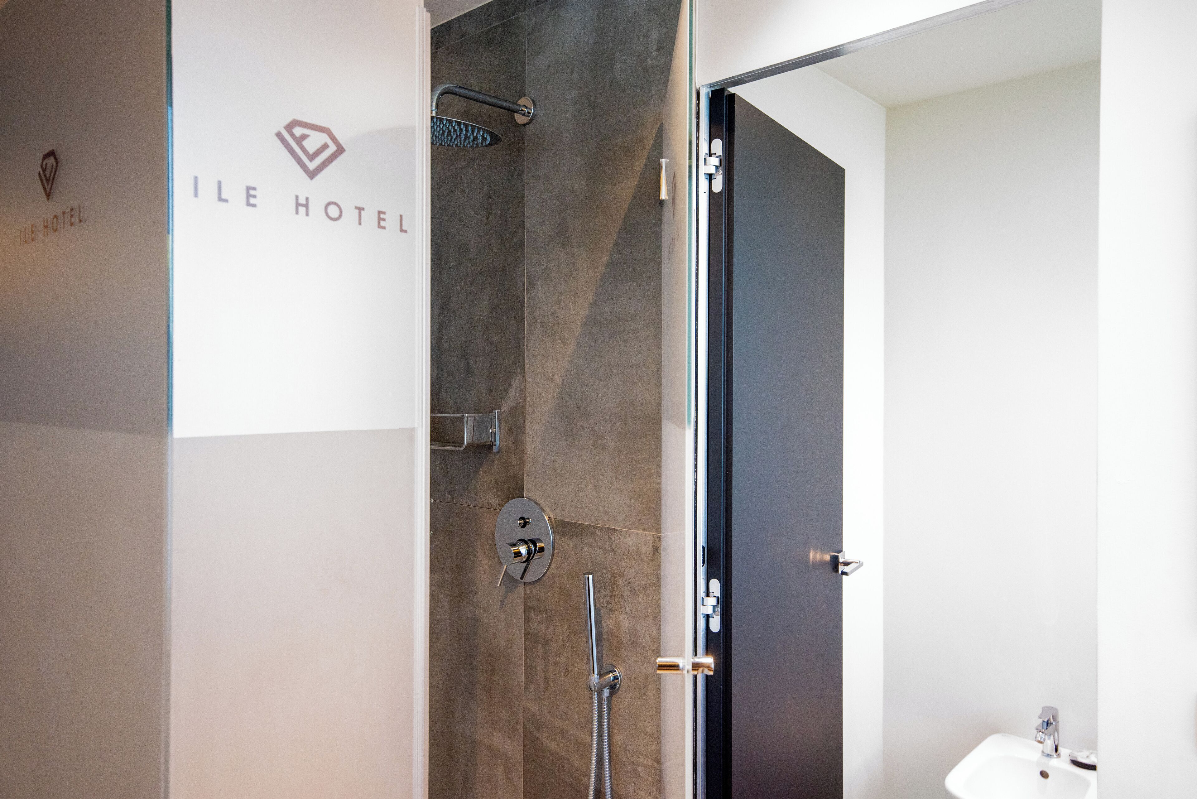 A modern bathroom with a glass-enclosed shower, a sink, and a door with a handle.