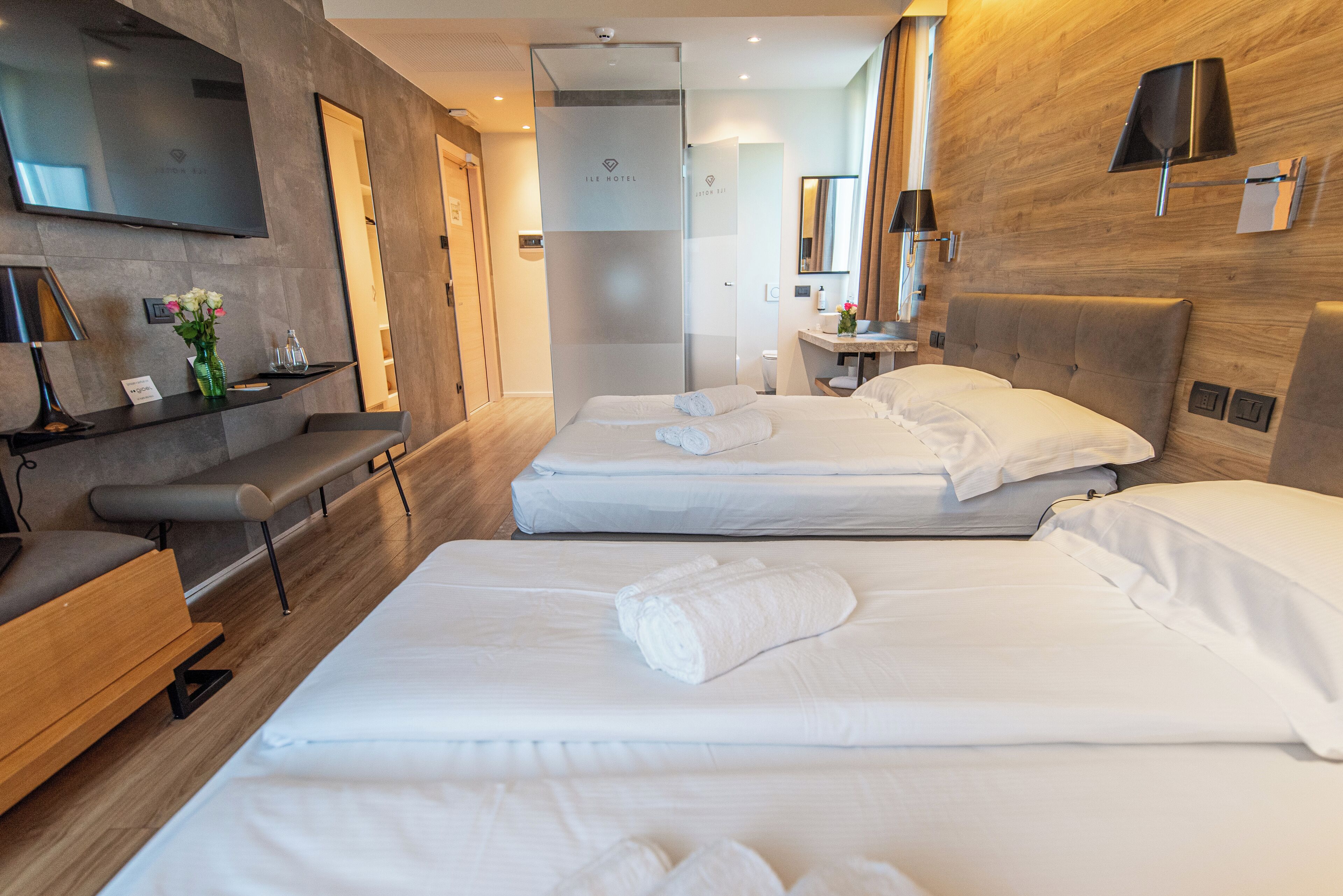 Une chambre d’hôtel avec deux lits, un bureau, une chaise, une télévision et un miroir.