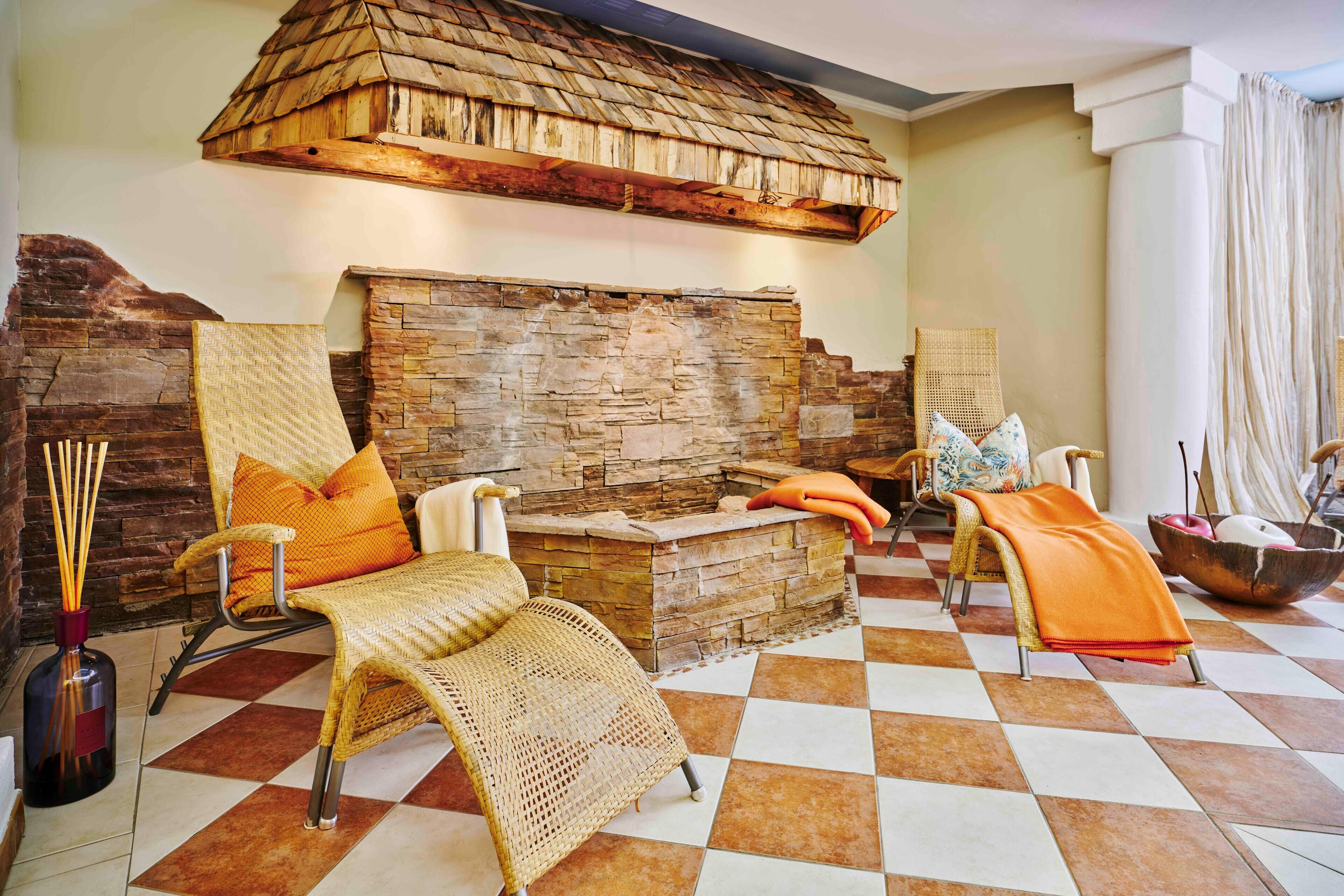 A room with a stone fireplace, wicker chairs, and a checkered floor.