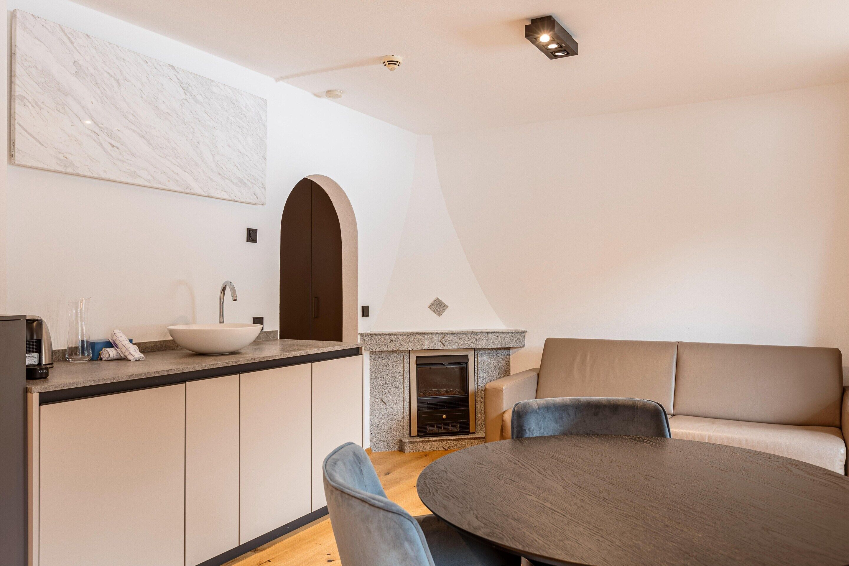 A modern kitchen with a white marble backsplash, a built-in oven, and a round dining table with chairs.
