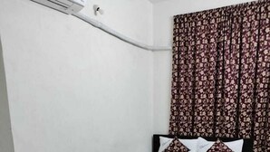 Una stanza piccola con un letto, un tavolino rotondo e due sedie gialle.