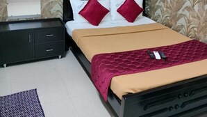 Una camera da letto con un letto, un comodino, una cassettiera e carta da parati decorata.