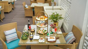 A wicker table set with a tiered dessert stand, a bottle of champagne, and a potted plant. - Park Plaza Jalandhar (Jalandhar)