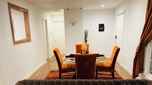 Un salon avec un canapé marron, une table à manger entourée de chaises orange et un vase rempli de fleurs.
