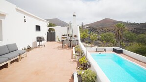 A rooftop terrace with a pool, outdoor furniture, and a view of terraced fields and mountains. - Casa MaVi - Vineyard with ocean view  (pool, privacy, scenic views, BBQ, AC)  (Tinajo)