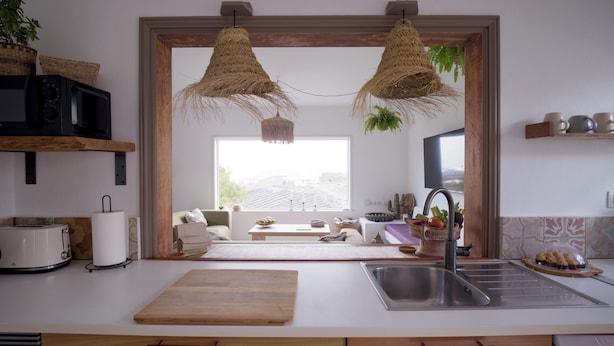 A modern kitchen with a large window, wooden cabinets, a stainless steel sink, and hanging woven light fixtures. - Casa MaVi - Vineyard with ocean view  (pool, privacy, scenic views, BBQ, AC)  (Tinajo)