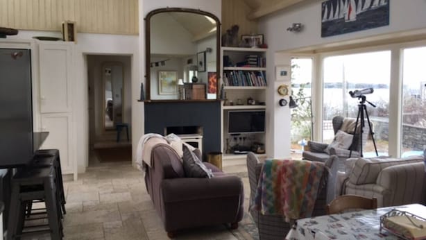 Ein geräumiges Wohnzimmer mit großem Fenster, Kamin und Bücherregal.