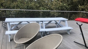 Eine Holzterrasse mit einem Picknicktisch und zwei Korbstühlen.