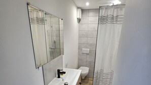 Ein modernes Badezimmer mit Duschkabine aus Glas, einem weißen Waschbecken mit Holzauszug und einem großen Spiegel.