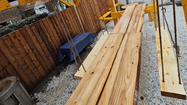 Eine Holzterrasse mit Schaukel und blauer Bank.
