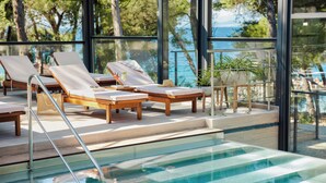 An indoor swimming pool with lounge chairs and a view of the sea. - Hotel Waterman Kaktus (Supetar)