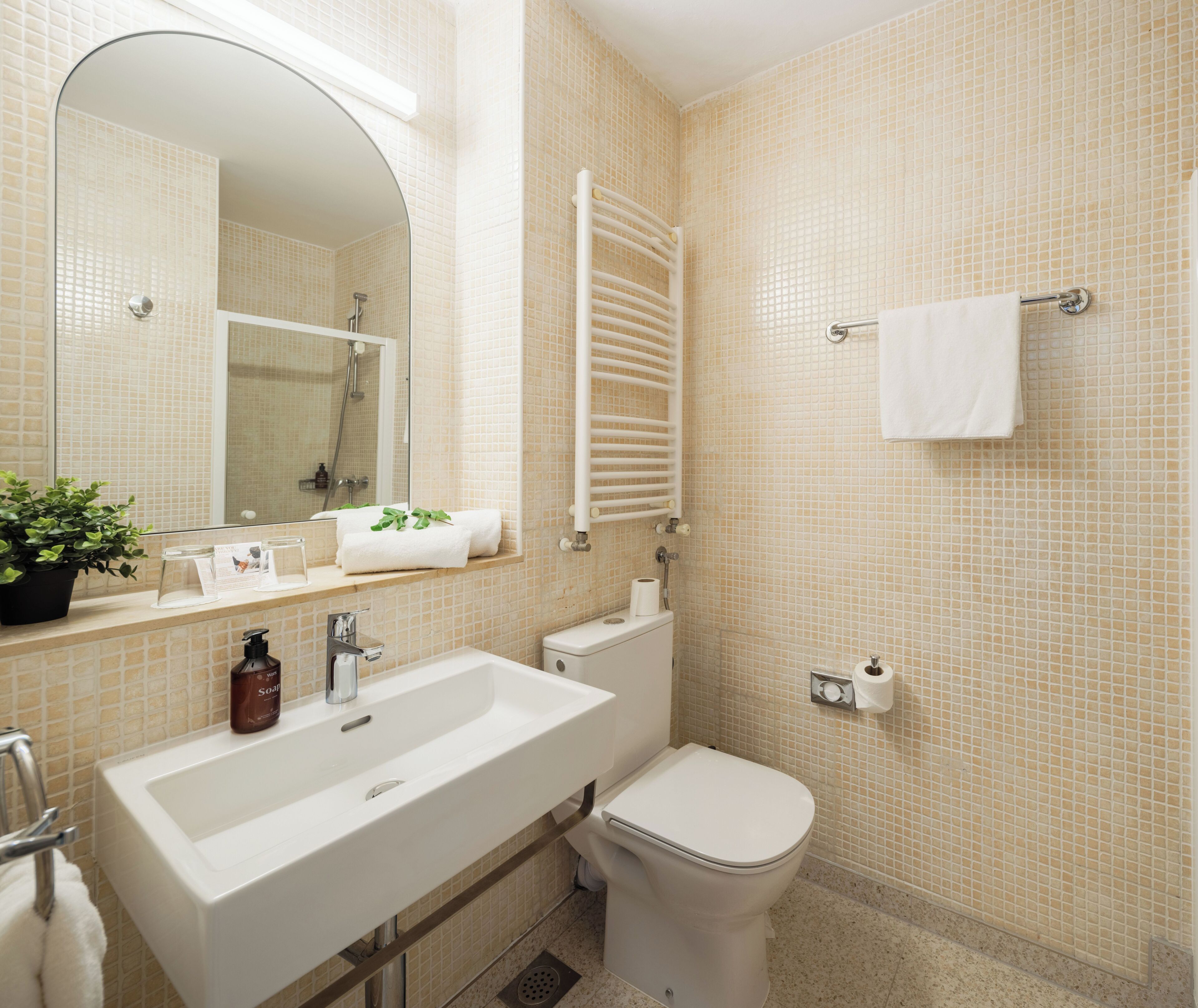 Un baño con lavamanos, inodoro y toallero.