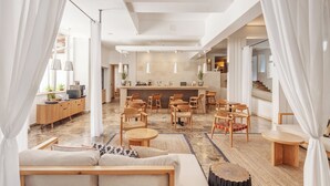 A modern living room with a sofa, coffee table, and chairs, a kitchen area with a bar, and a staircase leading to another level. - Hotel Waterman Kaktus (Supetar)