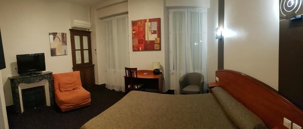 Una habitación de hotel con cama, televisión, escritorio, silla y chimenea.