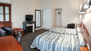 Een hotelkamer met twee bedden, een bureau, een stoel, een televisie en een kledingkast.