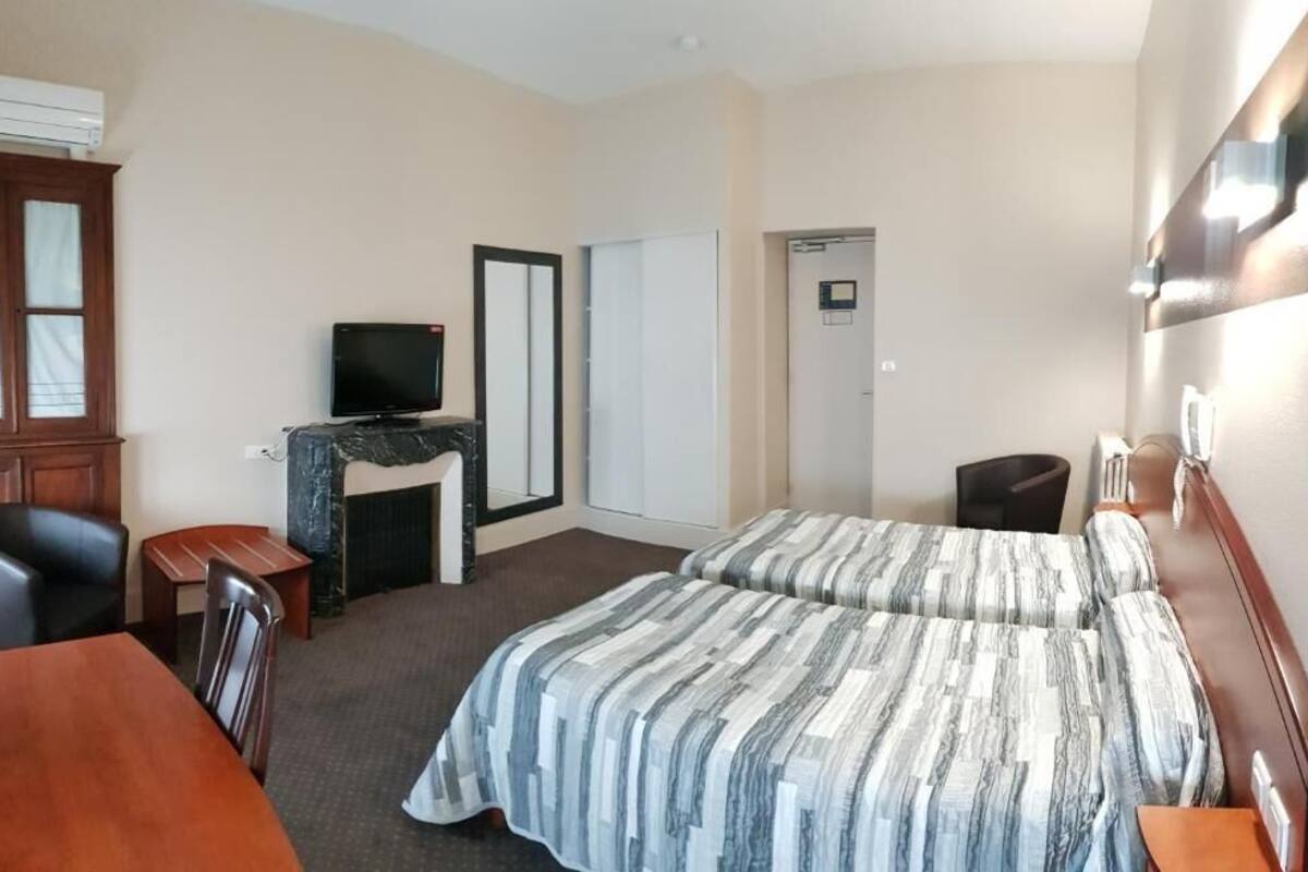 Een hotelkamer met twee bedden, een bureau, een stoel, een televisie en een kledingkast.