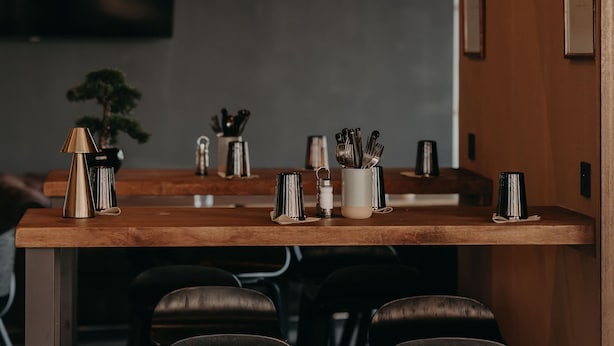 Een moderne keuken met een houten kookeiland, barkrukken, hangplanten en een hanglamp.