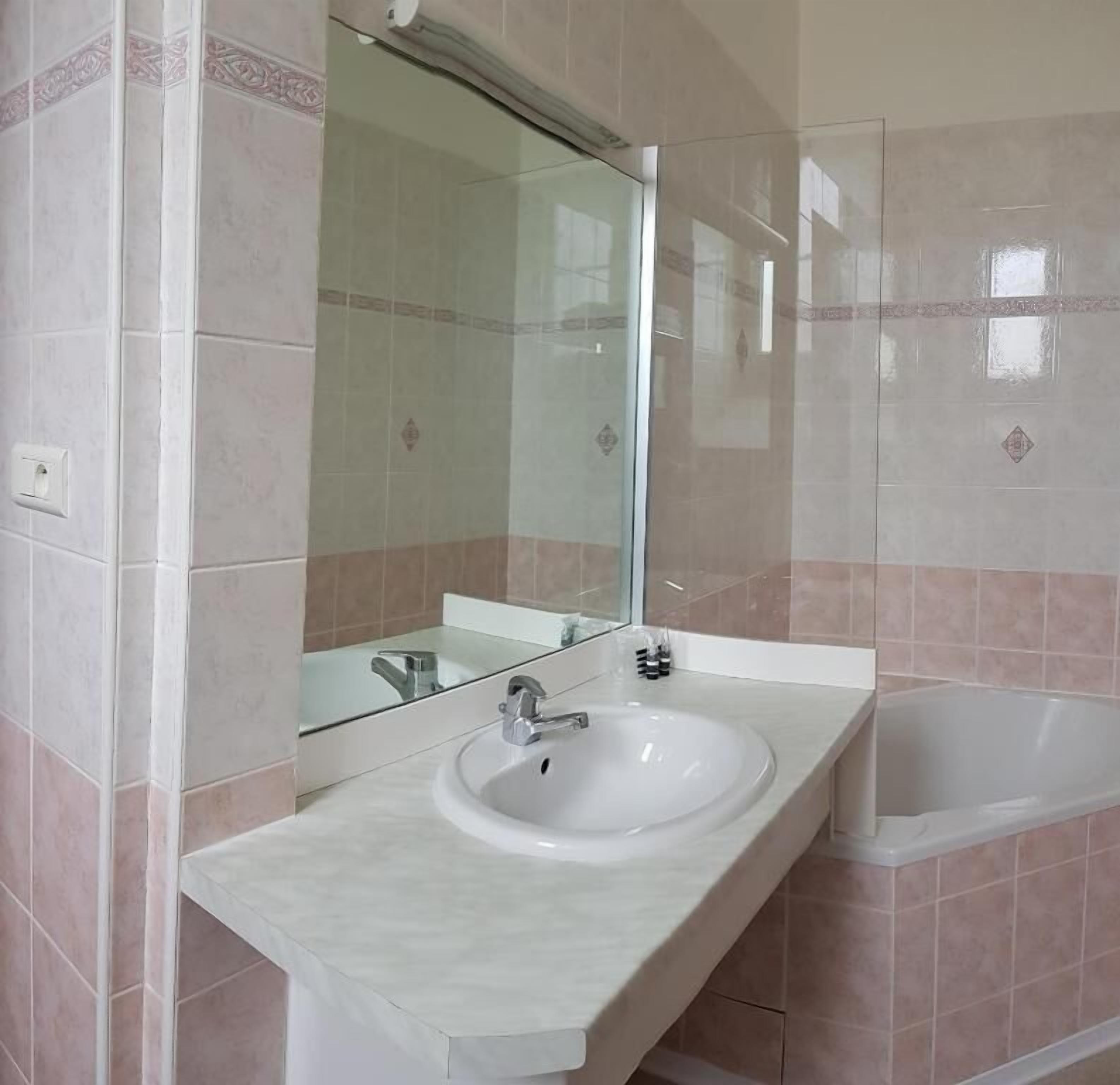 Ein Badezimmer mit einem weißen Waschbecken, einem Spiegel und einer Badewanne.