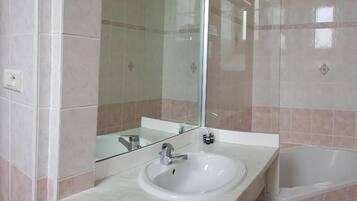 Ein Badezimmer mit einem weißen Waschbecken, einem Spiegel und einer Badewanne.
