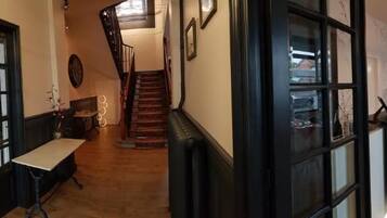 Un vestíbulo de hotel con una escalera, piso de madera y un área de comedor con mesas y sillas.