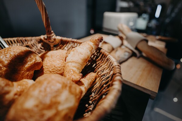 Een rieten mand vol met diverse gebakjes op een houten tafel.