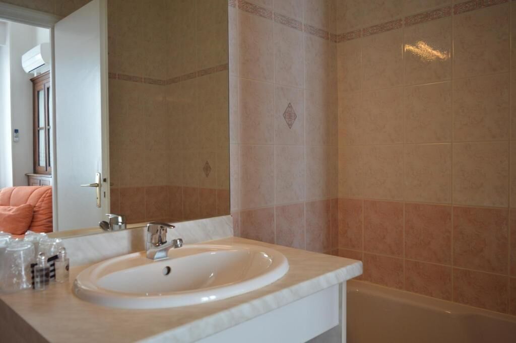 A bathroom with a sink, mirror, and bathtub.