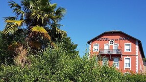 Een rood gebouw met balkons en het bord 'HOTEL DE LA PAIX' op de gevel.