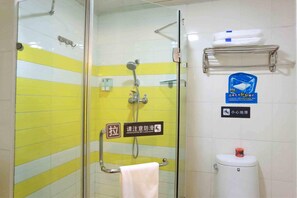 A bathroom with a glass shower enclosure, a towel rack, a toilet, and a shelf with toiletries.