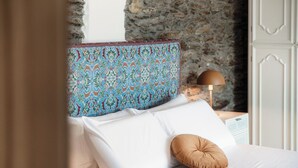 A bed with white linens, a patterned headboard, and a brown pillow. - Lost in Paradise  (San Siro)
