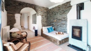 A cozy living room with a stone wall, a fireplace, and a wicker sofa. - Lost in Paradise  (San Siro)