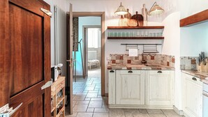 A kitchen with white cabinets, a tiled backsplash, and a wooden countertop. - Lost in Paradise  (San Siro)