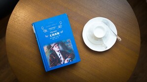 Een blauw boek met de titel 'Ulysses' naast een witte kop en schotel op een houten tafel.
