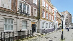 A row of traditional terraced houses with a prominent 'Warwick-House' sign, a black iron fence, and a clear street view.