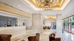 Un vestíbul d'hotel amb una recepció, seients de cuir, lluminàries i grans finestres.