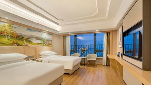 Habitació d'hotel amb dos llits, un escriptori amb una cadira, un quadre a la paret i una finestra gran amb vistes.